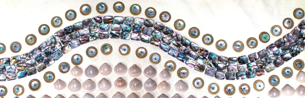 A mosaic featuring a wavy strip of iridescent square tiles, bordered by circular blue-and-gold disks—reminiscent of the unity found in an Opioid Treatment Program. Below the wave, rows of glossy, light-colored domed stones are neatly arranged.